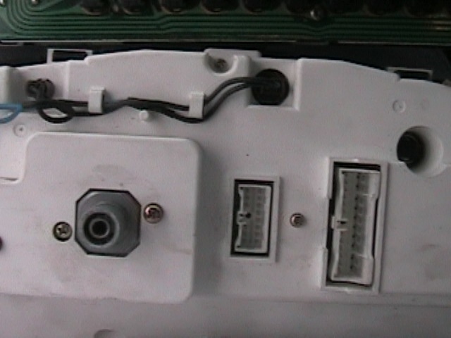 Back of instrument cluster showing wiring harness connectors and a central octagonal connector