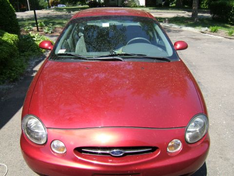 1998 Ford Taurus - Front view of a red 1998 Ford Taurus, showing its distinctive oval headlights and grille.