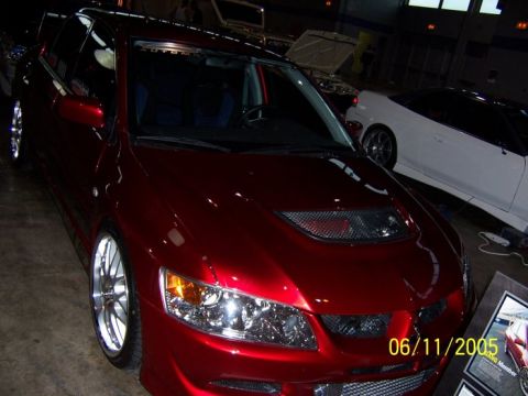 2005 Ford Focus - Red sedan with custom wheels and a prominent hood scoop is displayed indoors.