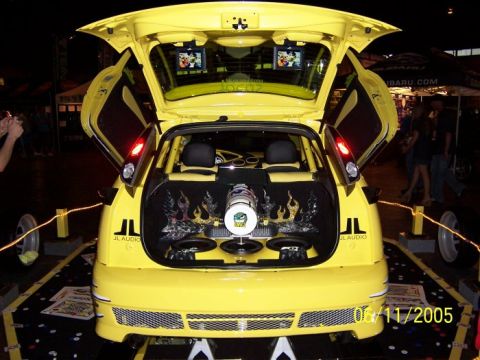 2005 Ford Focus - This yellow 2005 Ford Focus features a custom audio setup with multiple speakers and screens visible in the open trunk and doors.