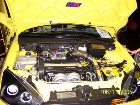 2005 Ford Focus - The engine bay of a yellow 2005 Ford Focus shows custom modifications and a Supermotors.net watermark.