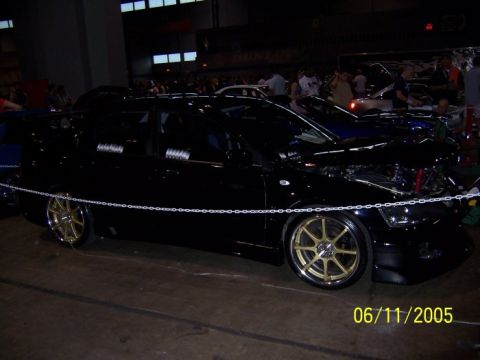 2005 Ford Focus - A black sedan with custom gold wheels is displayed indoors, with its hood open.