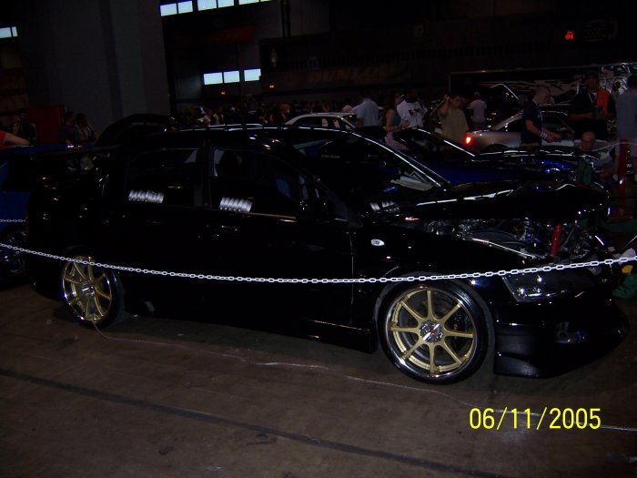 black sedan with gold rims, hood open, at a car show