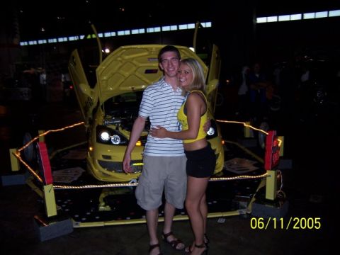2005 Ford Focus - A couple poses in front of a modified yellow 2005 Ford Focus at an event.