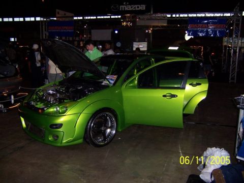 2005 Ford Focus - A lime green 2005 Ford Focus hatchback is displayed with its hood and driver's door open, custom wheels and aftermarket body modifications.