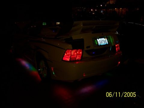 2005 Ford Focus - A yellow car with a spoiler and underglow lights is seen at night.