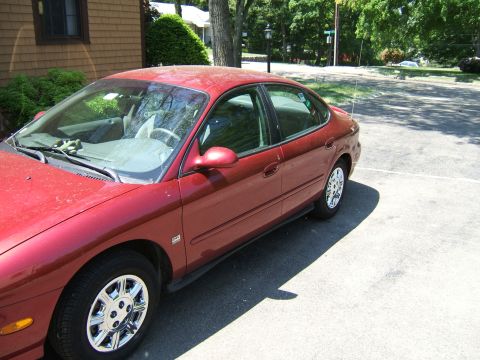 1998 Ford Taurus - A red 1998 Ford Taurus sedan is parked in a driveway on a sunny day.
