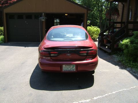 1998 Ford Taurus - Rear view of a red 1998 Ford Taurus sedan parked in front of a garage.