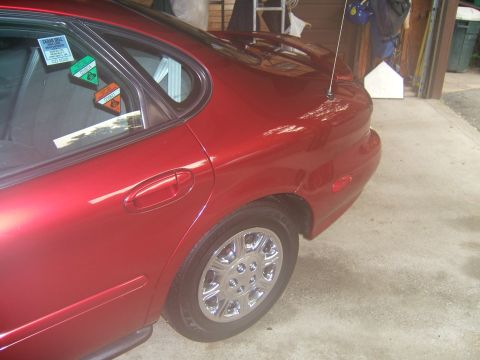 1998 Ford Taurus - Rear quarter view of a red 1998 Ford Taurus sedan with tinted rear windows displaying stickers.