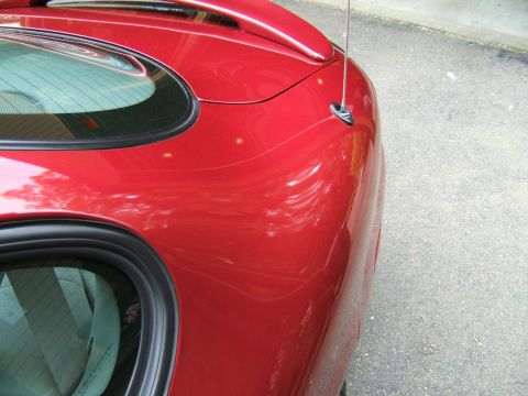 1998 Ford Taurus - Close-up of a red car's rear quarter panel, showing reflections and a visible antenna.
