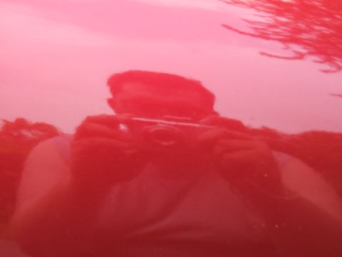 1998 Ford Taurus - Reflection of a person holding a camera is visible on the shiny red surface of a vehicle.