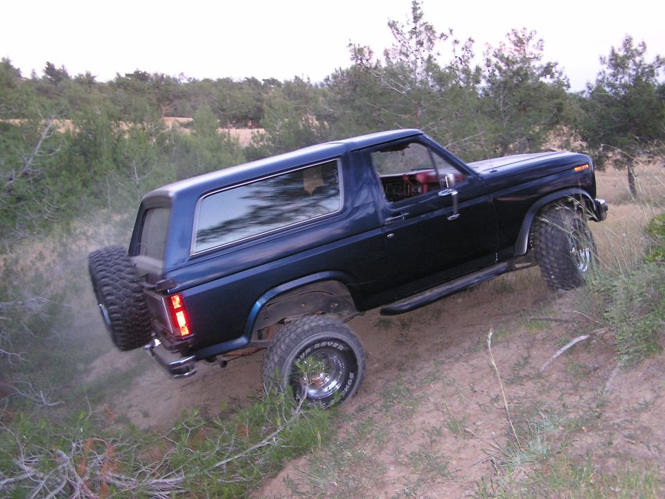 Dark blue 1986 Ford Bronco driving off-road