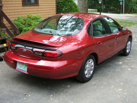 1998 Ford Taurus - This red 1998 Ford Taurus sedan is shown from the rear, a spoiler and a license plate reading 104-545.