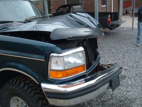 1994 Ford Bronco - Front end damage on a Ford truck, with another pickup visible behind it.