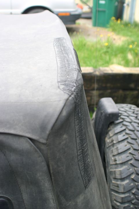 2003 Jeep TJ - The soft top of a vehicle has been repaired with tape over a rip.