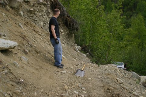 2003 Jeep TJ - A man observes an off-road vehicle navigating a steep, rocky incline surrounded by dense foliage.