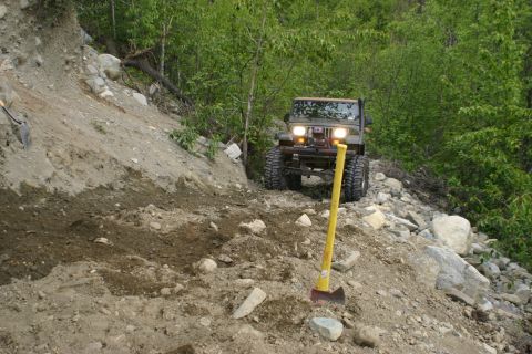 2003 Jeep TJ - A Jeep Wrangler navigates a challenging off-road path, with a shovel and axe nearby.