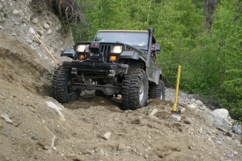 2003 Jeep TJ - Jeep Wrangler tackling a challenging off-road trail with steep dirt and rocky terrain.