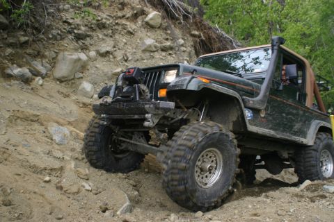 2003 Jeep TJ - This modified Jeep Wrangler YJ is navigating a steep, rocky incline on an off-road trail.