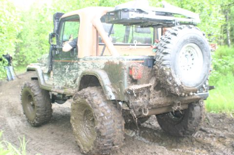 2003 Jeep TJ - A heavily mud-splattered Jeep Wrangler navigates a challenging off-road course.
