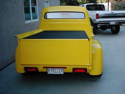 1978 Ford Bronco - Rear view of a bright yellow pickup truck with a black bed liner and custom license plate.