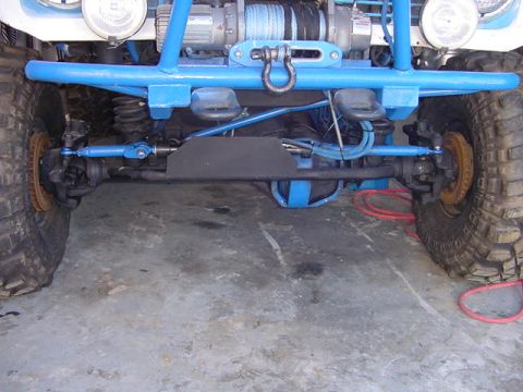 1971 Ford Bronco - Close-up of a modified off-road vehicle's front axle, suspension, and winch.