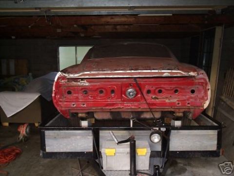 2005 Ford Mustang - Rear view of a red 1969 Ford Mustang undergoing restoration, mounted on a trailer.