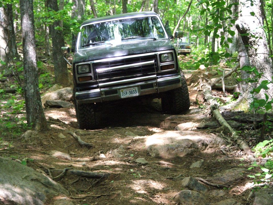 Dark SUV with a chrome grille and license plate JSV-3033 navigating a rocky trail