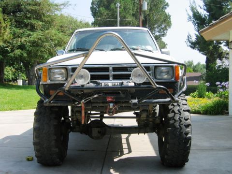 1985 Ford Bronco - This modified Toyota truck features a prominent roll cage and winch, with oversized tires for off-road use.