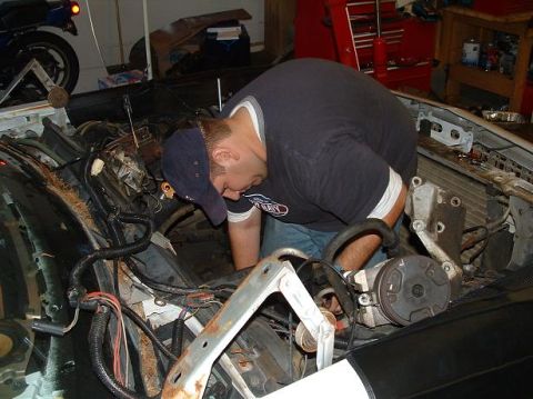 1985 Ford Crown Victoria LTD - Mechanic working on the engine of a car, likely during a repair or swap.