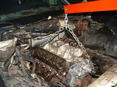 1985 Ford Crown Victoria LTD - The engine is being removed from the car using an engine hoist and chains.
