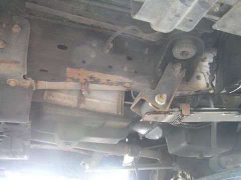 2000 Ford Excursion - The underside of the vehicle reveals the transmission and frame structure, with visible signs of wear and rust.