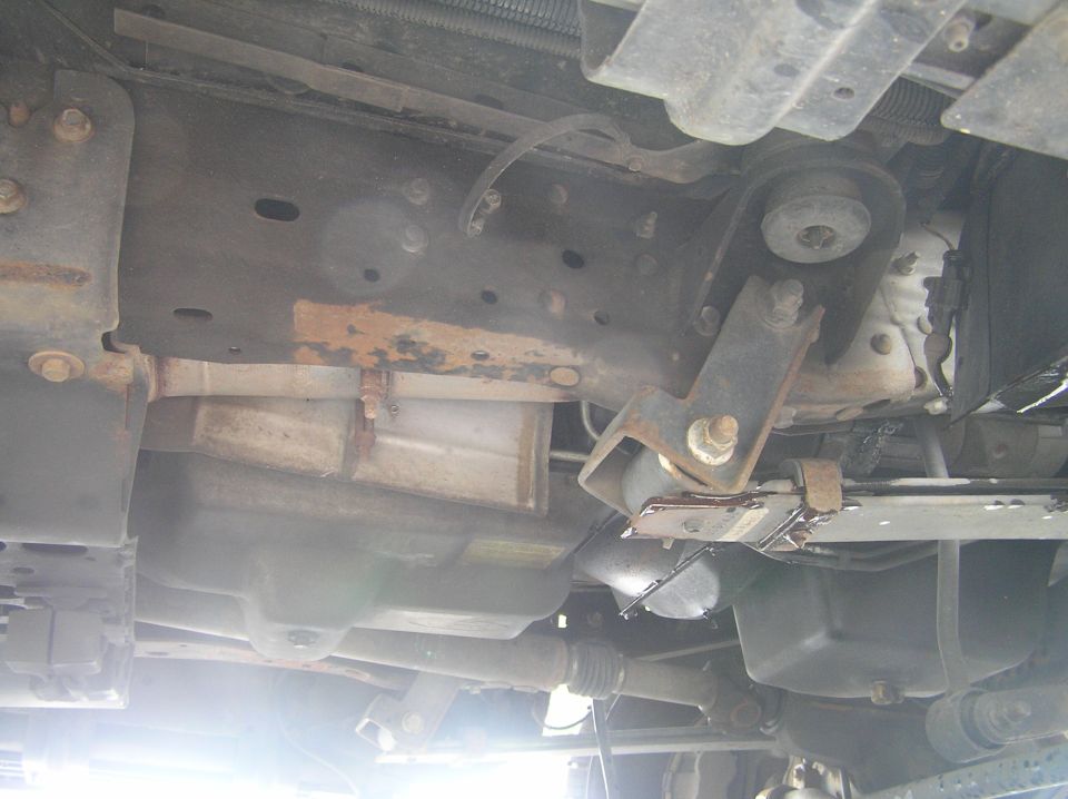 Underbody view of vehicle frame, crossmember, and drivetrain with surface rust