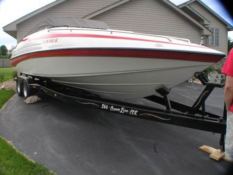 2000 Ford Excursion - A white and red striped boat is parked on a trailer in front of a house.