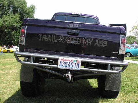1979 Ford Bronco - A custom purple pickup truck is shown from the rear, a large aftermarket bumper and a humorous decal.