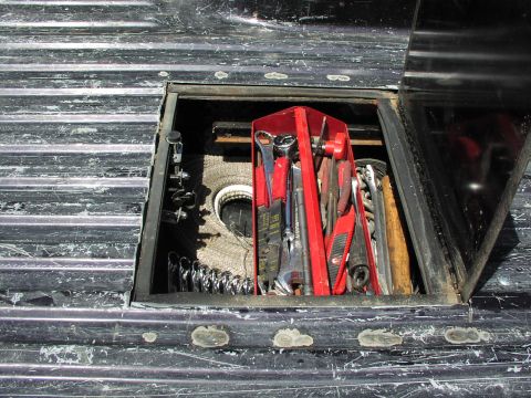 1979 Ford Bronco - A red toolbox filled with various wrenches and tools is stored in a compartment within a truck bed.