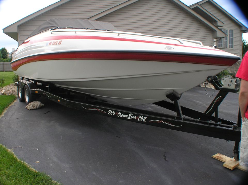 Red and white Crownline 266 CCR boat on black trailer in driveway