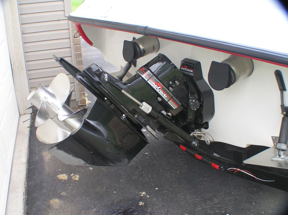 Black MerCruiser stern drive with stainless dual props on white boat transom