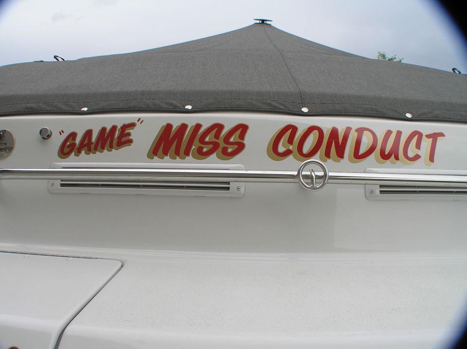 White boat transom with red and gold "GAME" MISS CONDUCT lettering and stainless rail