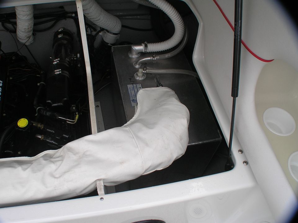Boat engine bay with black tank, hoses, and white fiberglass hull