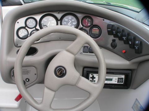 1997 Crownline 266 CCR - Close-up of a boat's helm, showing the steering wheel, instrument cluster, and control panel.