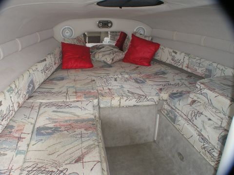 1997 Crownline 266 CCR - Interior view of a boat cabin, upholstered seating and red accent pillows.