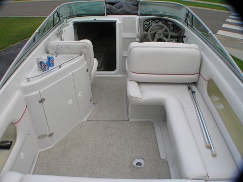 1997 Crownline 266 CCR - The interior of a boat shows white seating and gray carpeting, with a sink and a few cans of beer.
