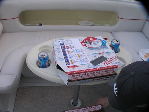1997 Crownline 266 CCR - A pizza box and two cans of soda sit on a table inside a boat's cabin.