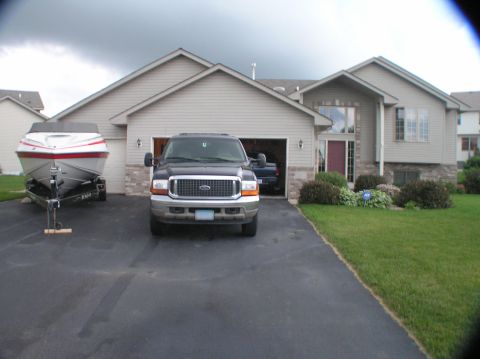1997 Crownline 266 CCR - A black Ford truck is parked in the driveway next to a boat on a trailer.
