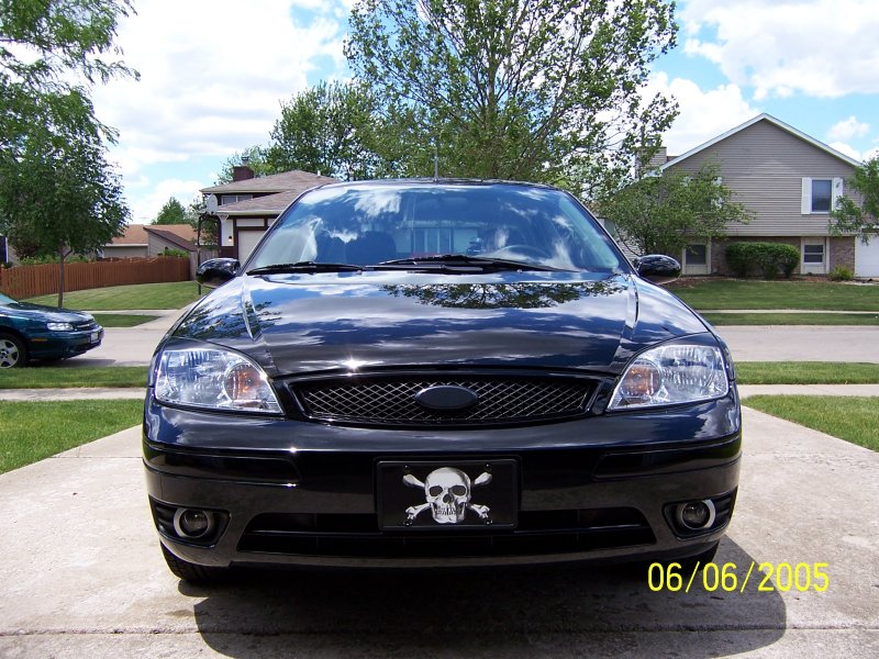 Front view of a black sedan with a skull and crossbones license plate frame. Date stamp shows 06/06/2005