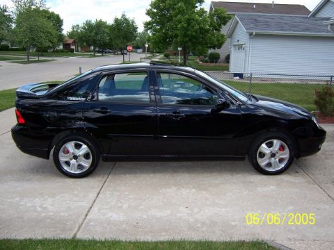 2005 Ford Focus - A black sedan is parked on a concrete driveway with a suburban house in the background. The date 06/06/2005 is visible.