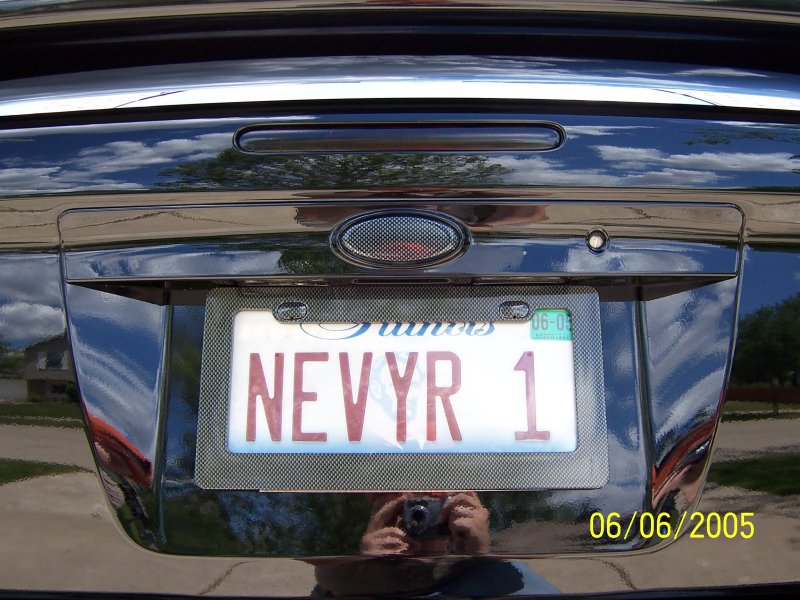 Rear of a black car with a license plate that reads NEVVR 1. A date stamp shows 06/06/2005