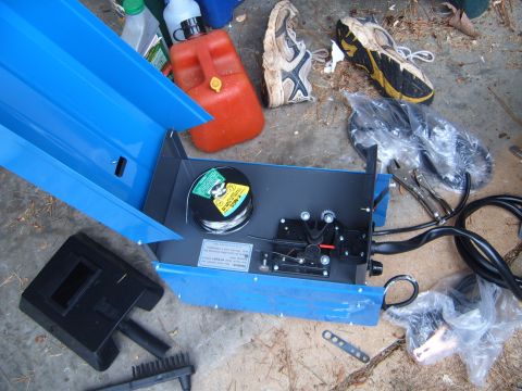 1988 Ford Bronco - A blue welding machine is shown with its wire spool, a welding mask, and a red gas can, along with other accessories scattered items.