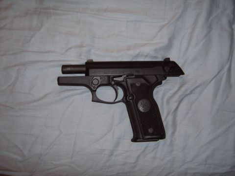 1988 Ford Bronco - A black semi-automatic pistol is shown against a light blue, wrinkled fabric background.